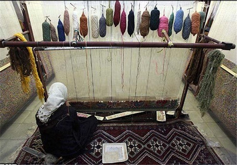 بافنده اصفهانی در حال گره زدن قالی با دار عمودی و استفاده از تکنیک گره فارسی؛ نمایش دهنده رجشمار بالا و ظرافت بافت.